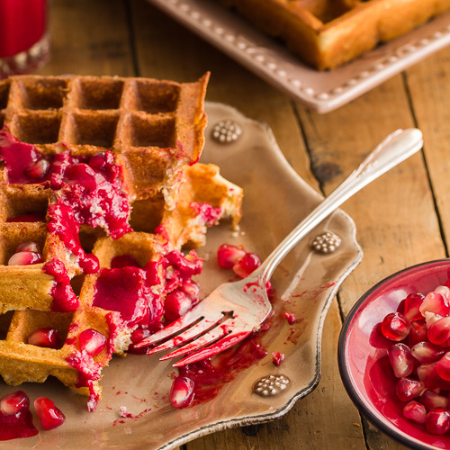 small plate of golden waffles with raspberry sauce 