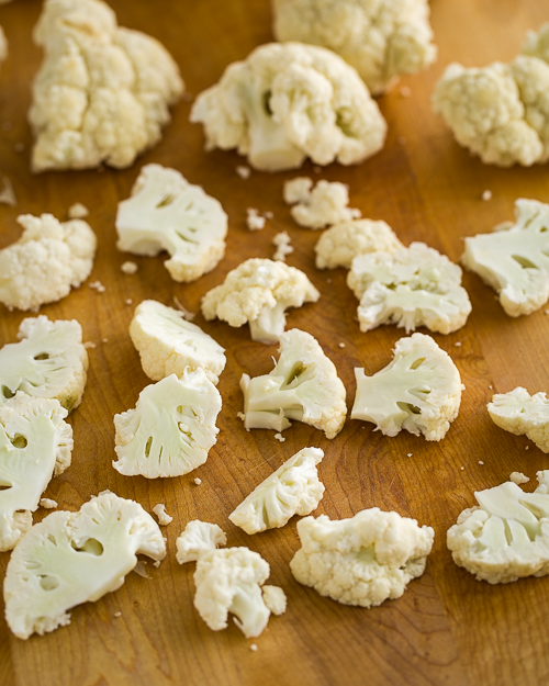 Scattered cauliflower florets on a cutting board.