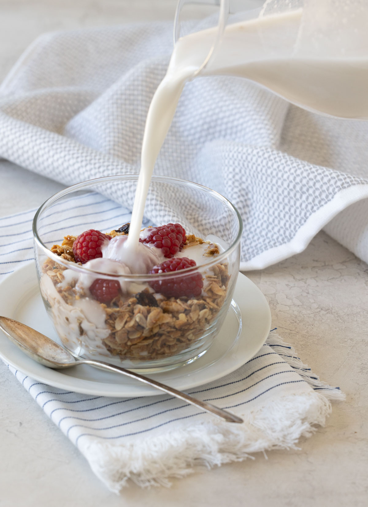 Homemade granola with berries and coconut milk pouring into the bowl,