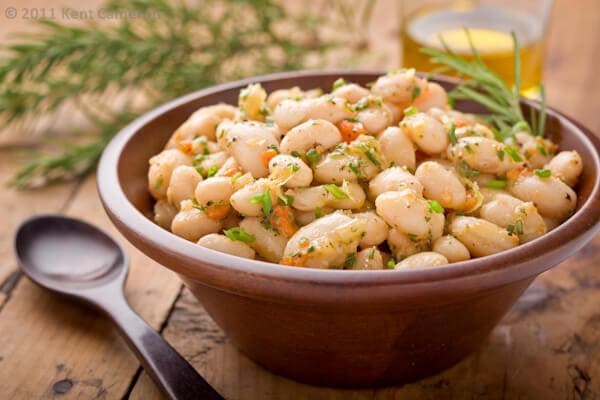 A wooden bowl of white bean salad. 
