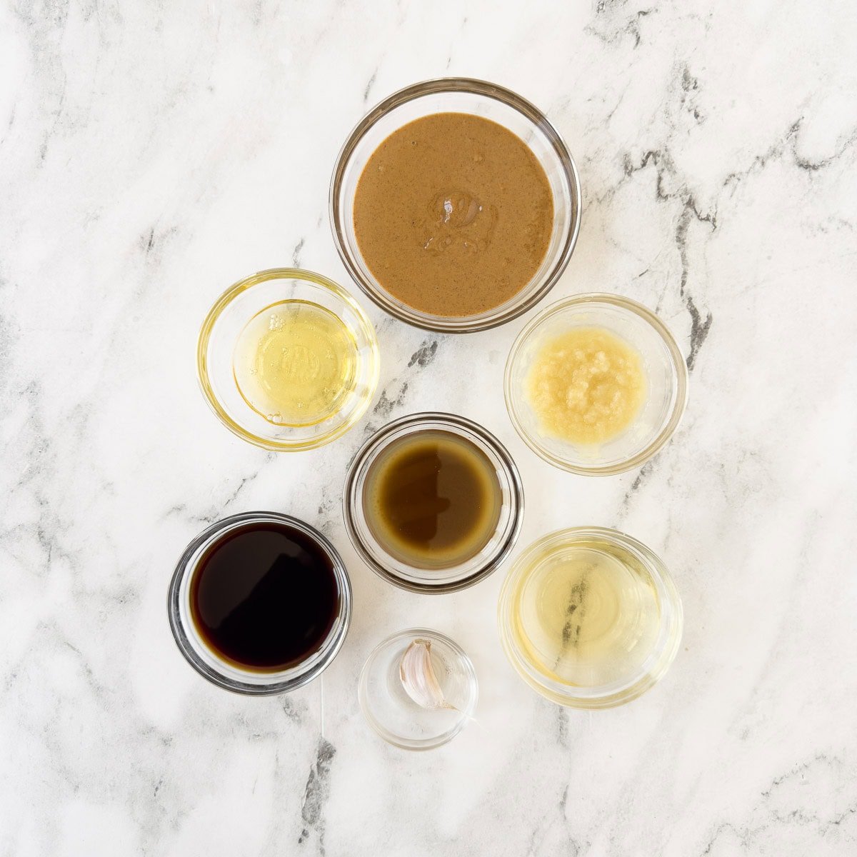 Ingredients for creamy asian dipping sauce with almond butter, ginger, garlic, soy sauce, oil, and honey.
