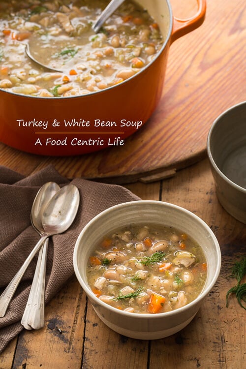 A bowl and a pot of hearty turkey white bean soup.