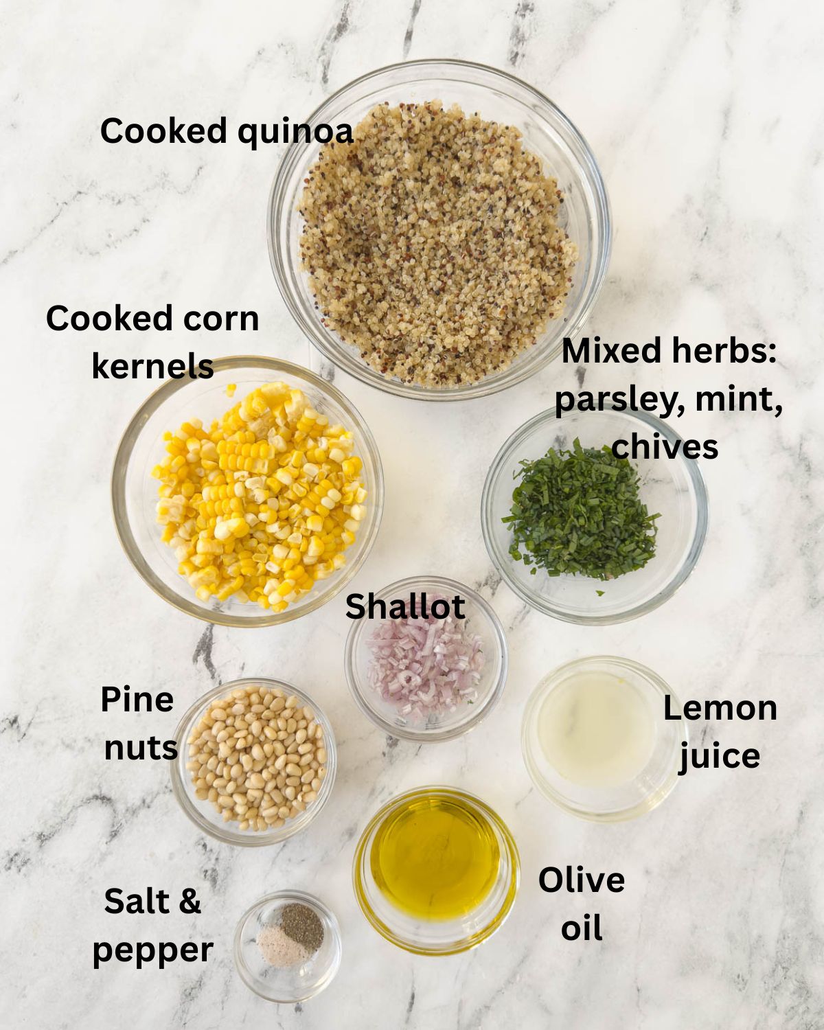 Ingredients for a quinoa corn salad with herbs, in prep bowls on a marble counter.