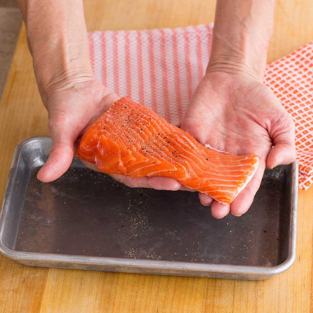 Piece of raw salmon, uneven in thickness with a thicker and thinner end.