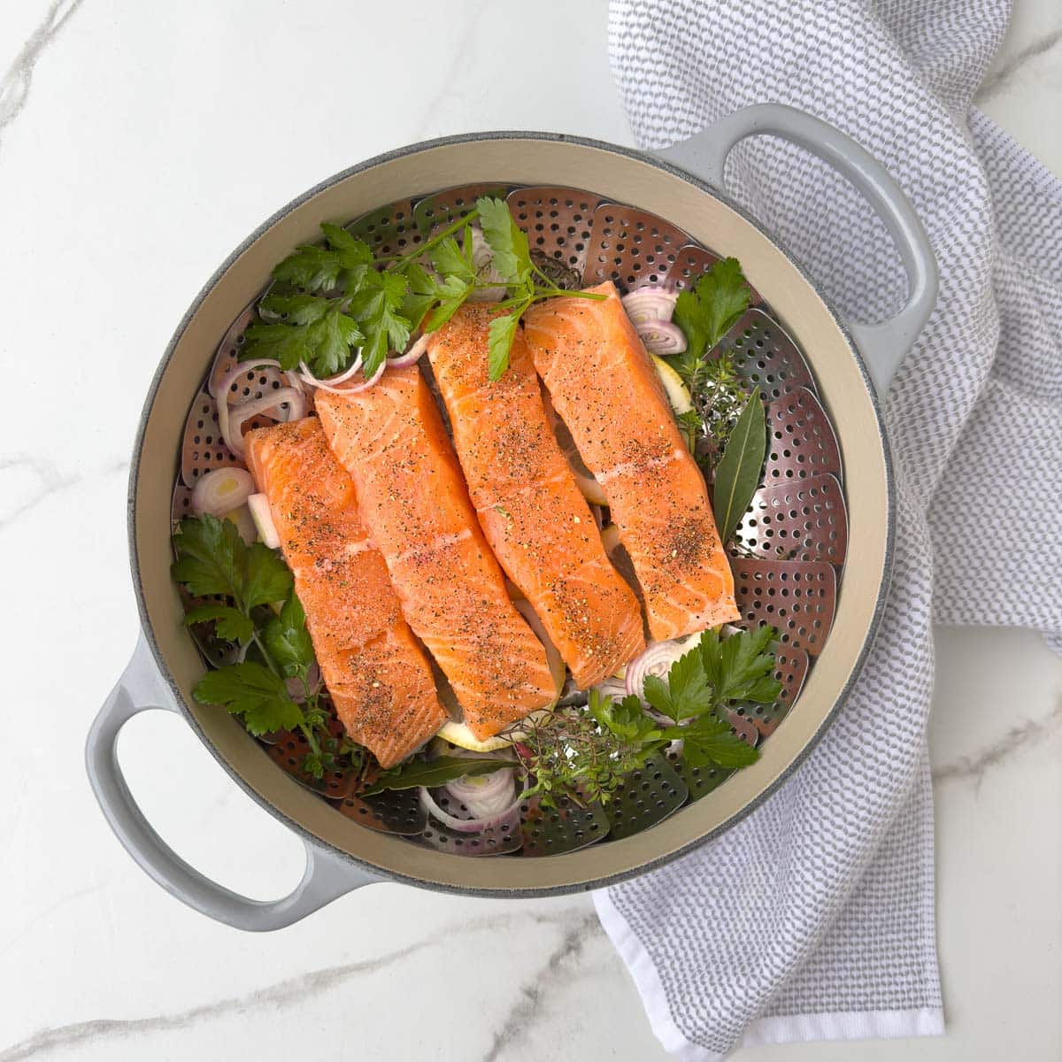 Salmon filets in a pot with lemon, herbs, shallots, ready for steaming. 