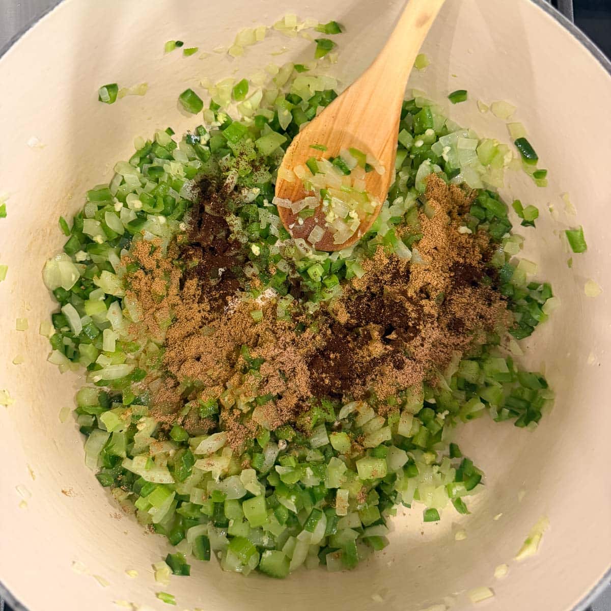 Adding spices to a pot of sautéing vegetables as a soup base.