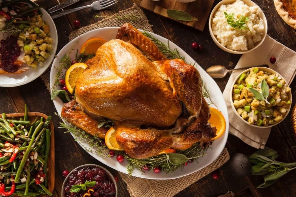 A Thanksgiving table with a golden roast turkey at the center.