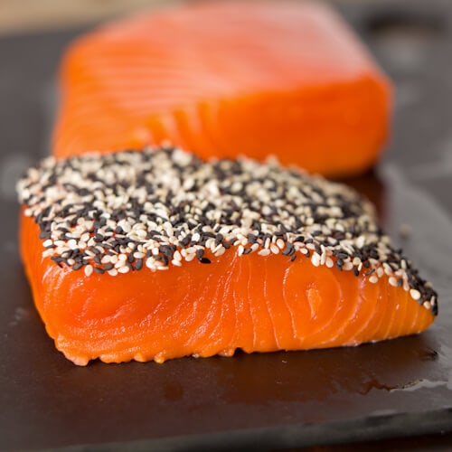 Coating bright orange salmon filets with sesame seeds for a crusted top.