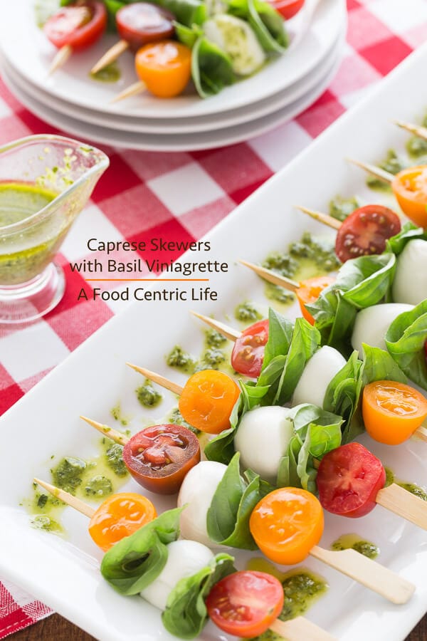 Caprese skewers on a serving platter drizzled with basil dressing.