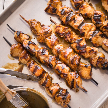 Grilled chicken kabobs glazed with hoisin sauce on a baking sheet.