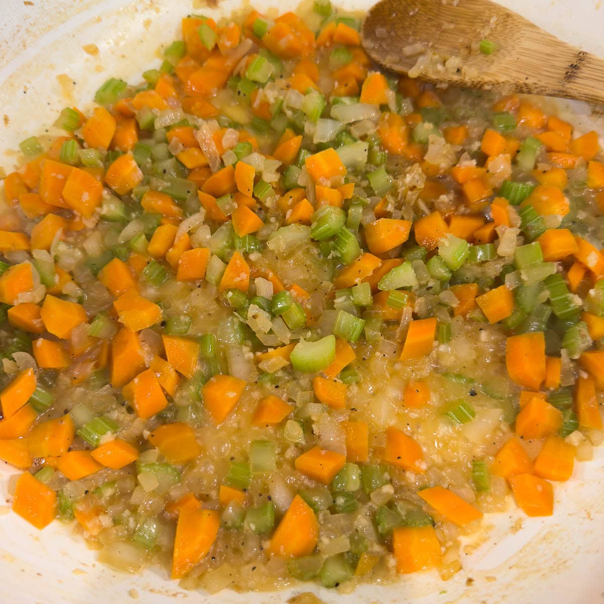 Adding wine to apan of sauted vegetables and garlic to deglaze.
