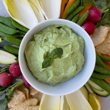 Close up of creamy basil and avocado dip in white bowl.