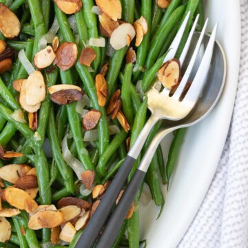 A bowl of bright green beans almondine with toasted buttered almonds.