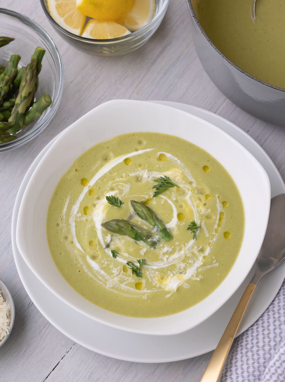 Beautiful green asparagus soup in a white bowl with tasty garnishes ready to eat. 