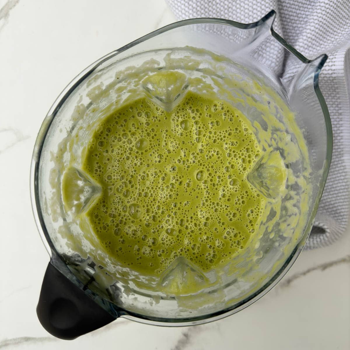 Bright green asparagus soup pureed in a blender container, ready to serve.