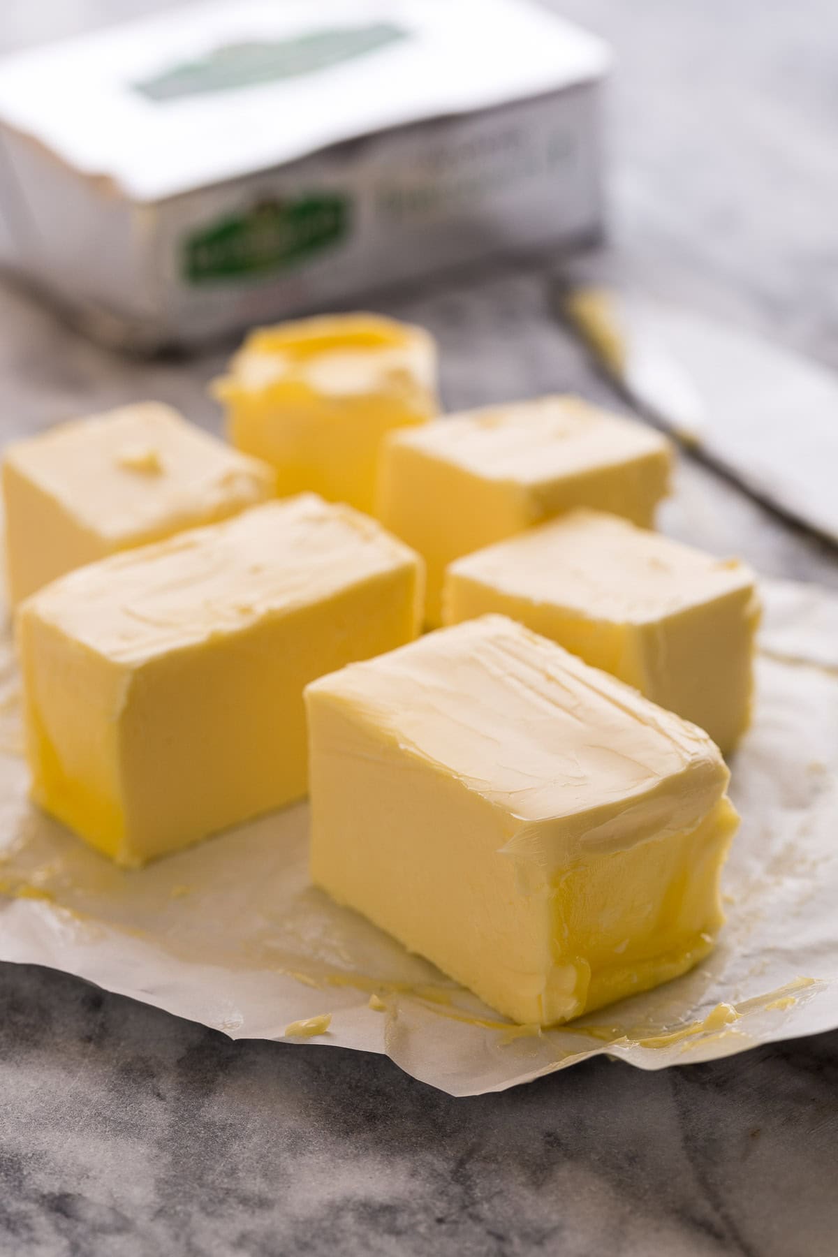 Cubes of butter on silver butter wrappers on a counter.