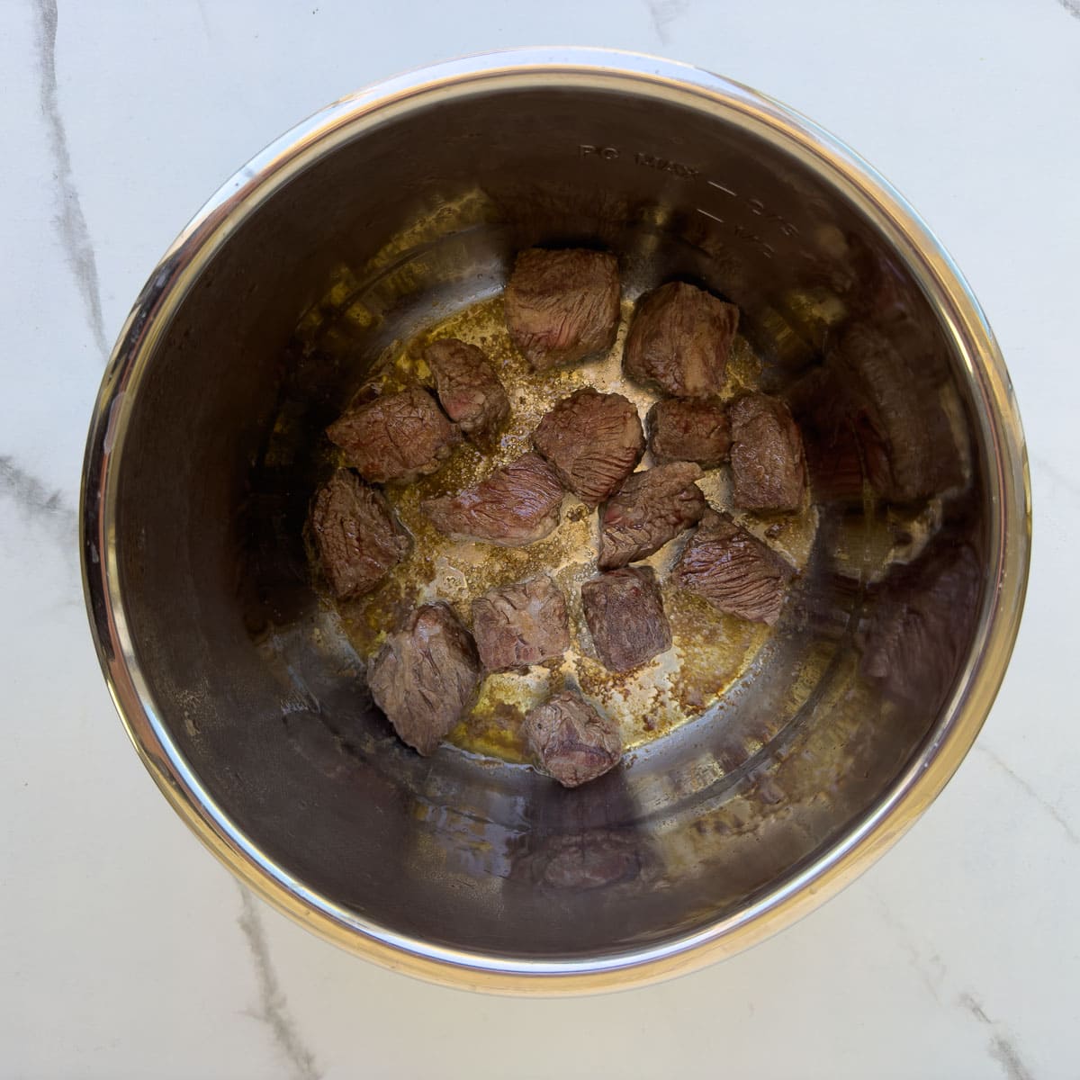 Cubes of beef cooking in an Instant Pot for stew.