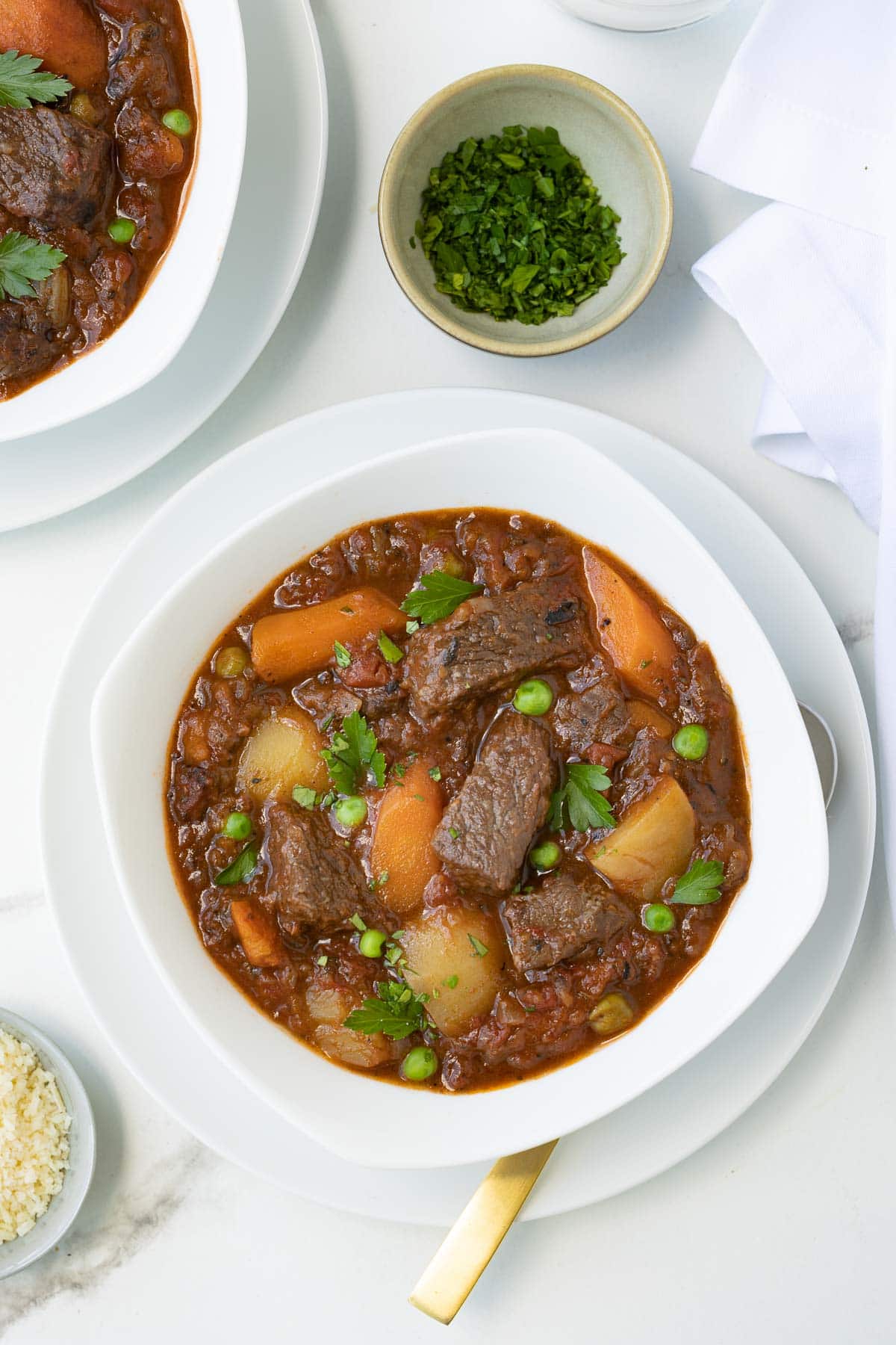 A white bowl full of rich Instant Pot beef stew with vegetables. 