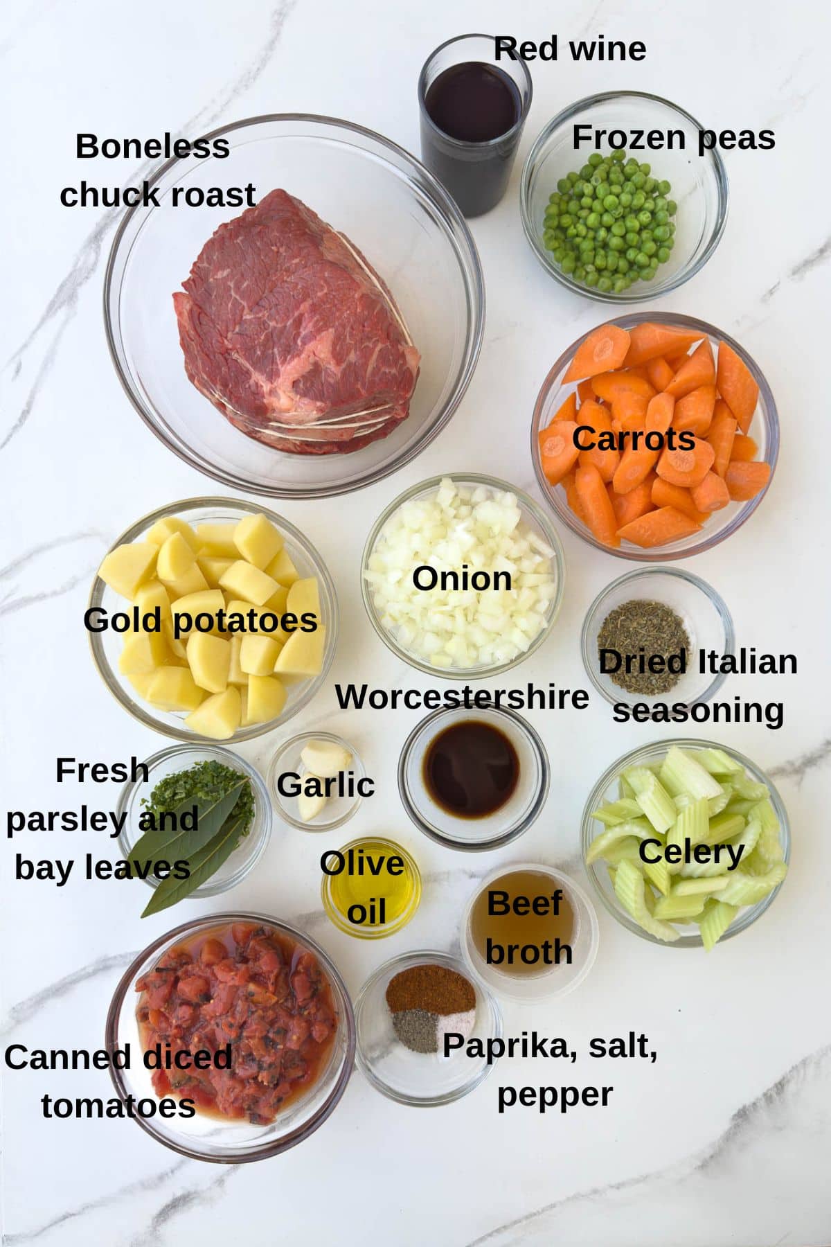 Labeled ingredients for beef stew on marble counter. 