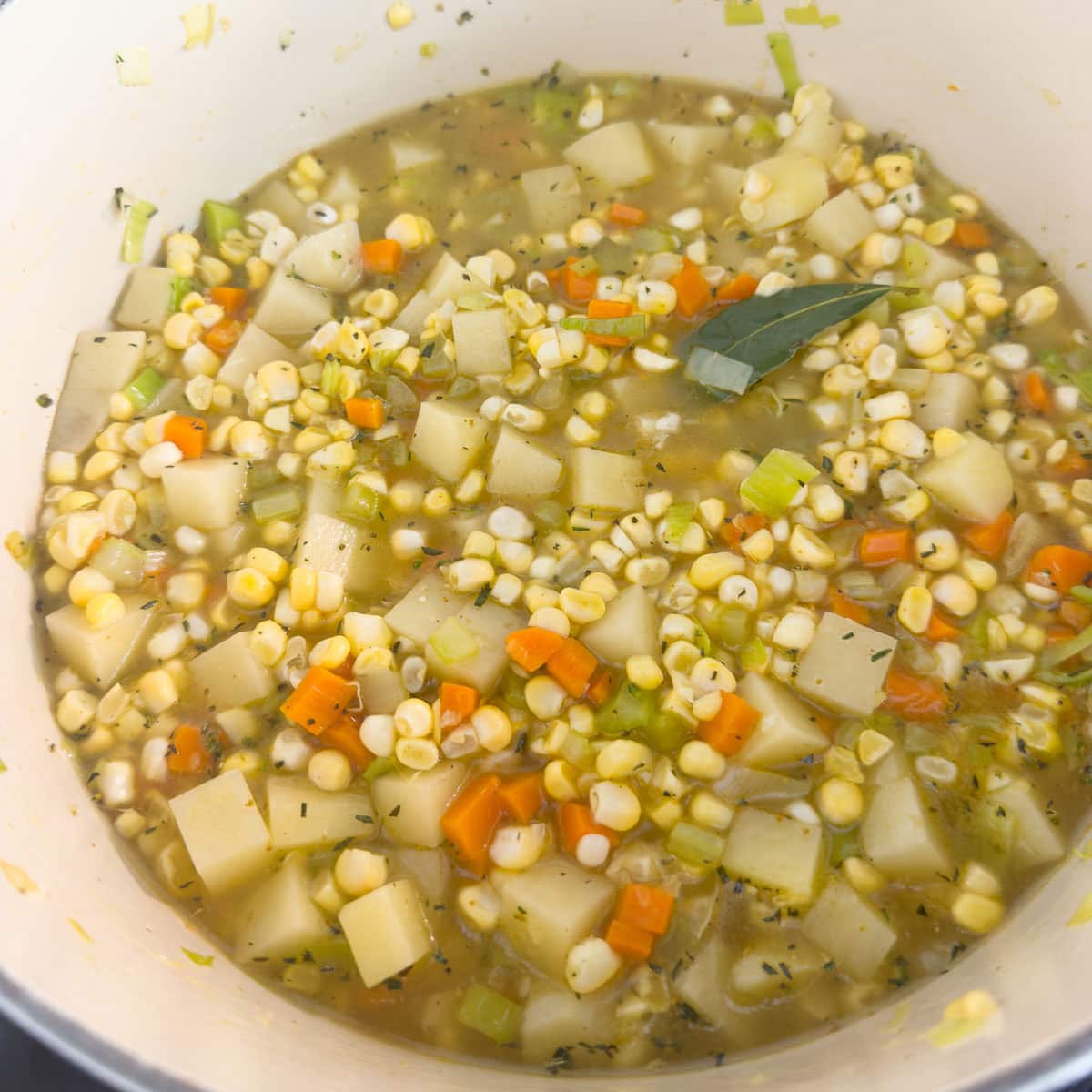 Corn and broth added to a pot for making corn and potato chowder.