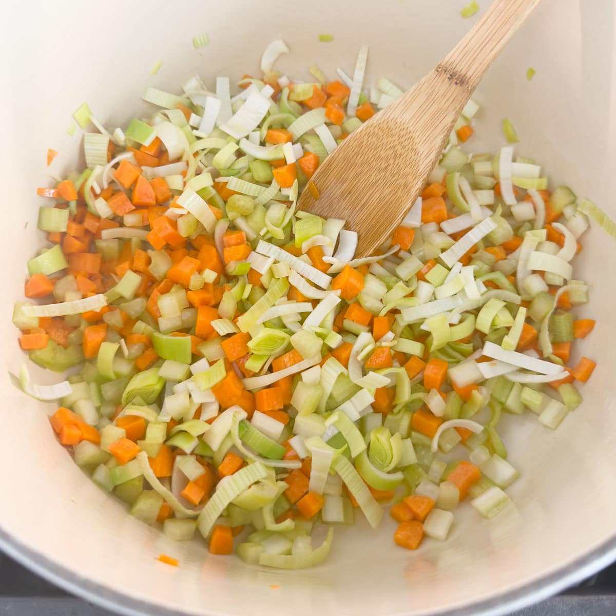 Sautéing celery, carrots, and leeks in a pot.