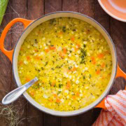 An orange dutch oven with bright yellow corn and potato chowder