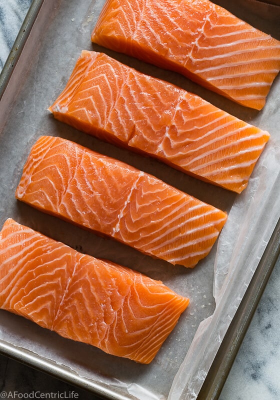 Raw, bright orange salmon filets on a tray.