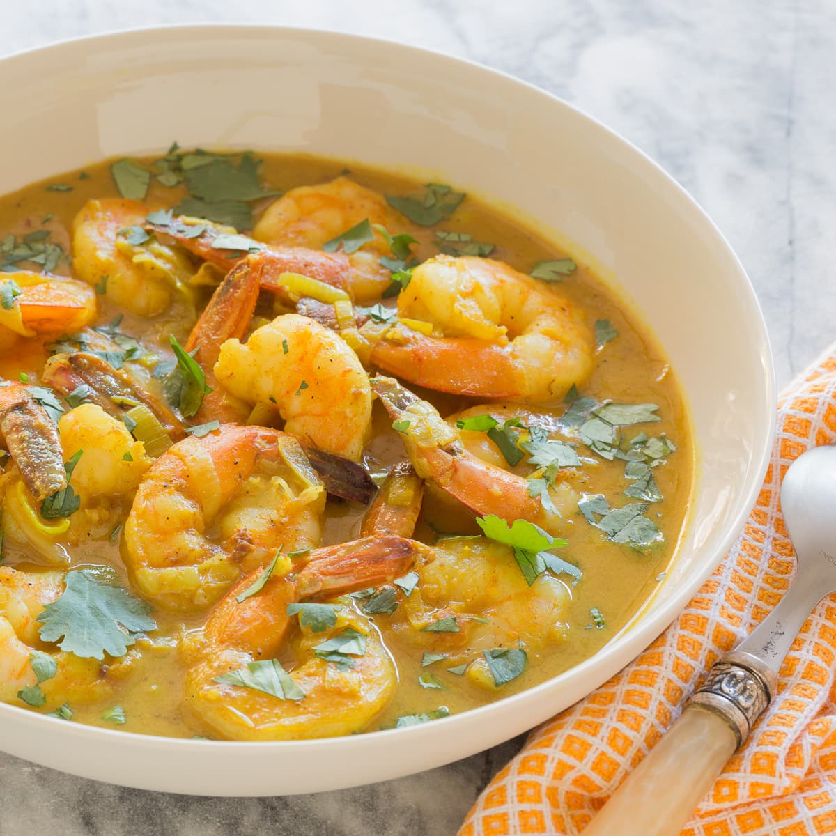 Orangey colored coconut curry shrimp in a bowl.