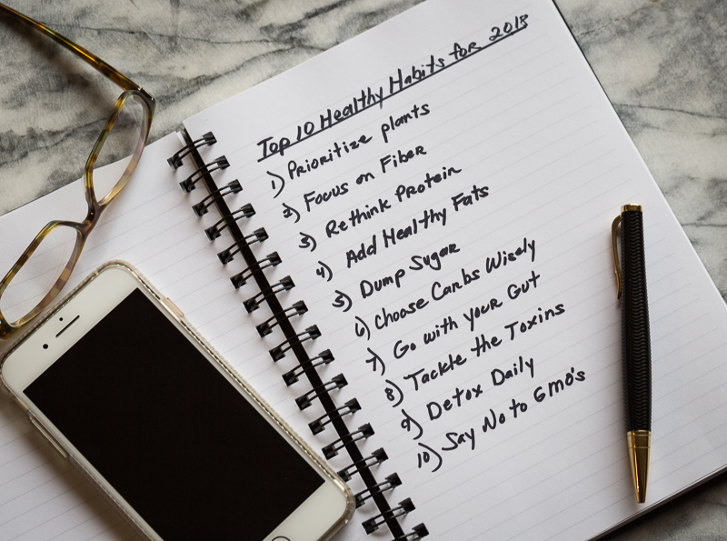 A journal listing 10 healthy habits with a cell phone, pen and glasses.