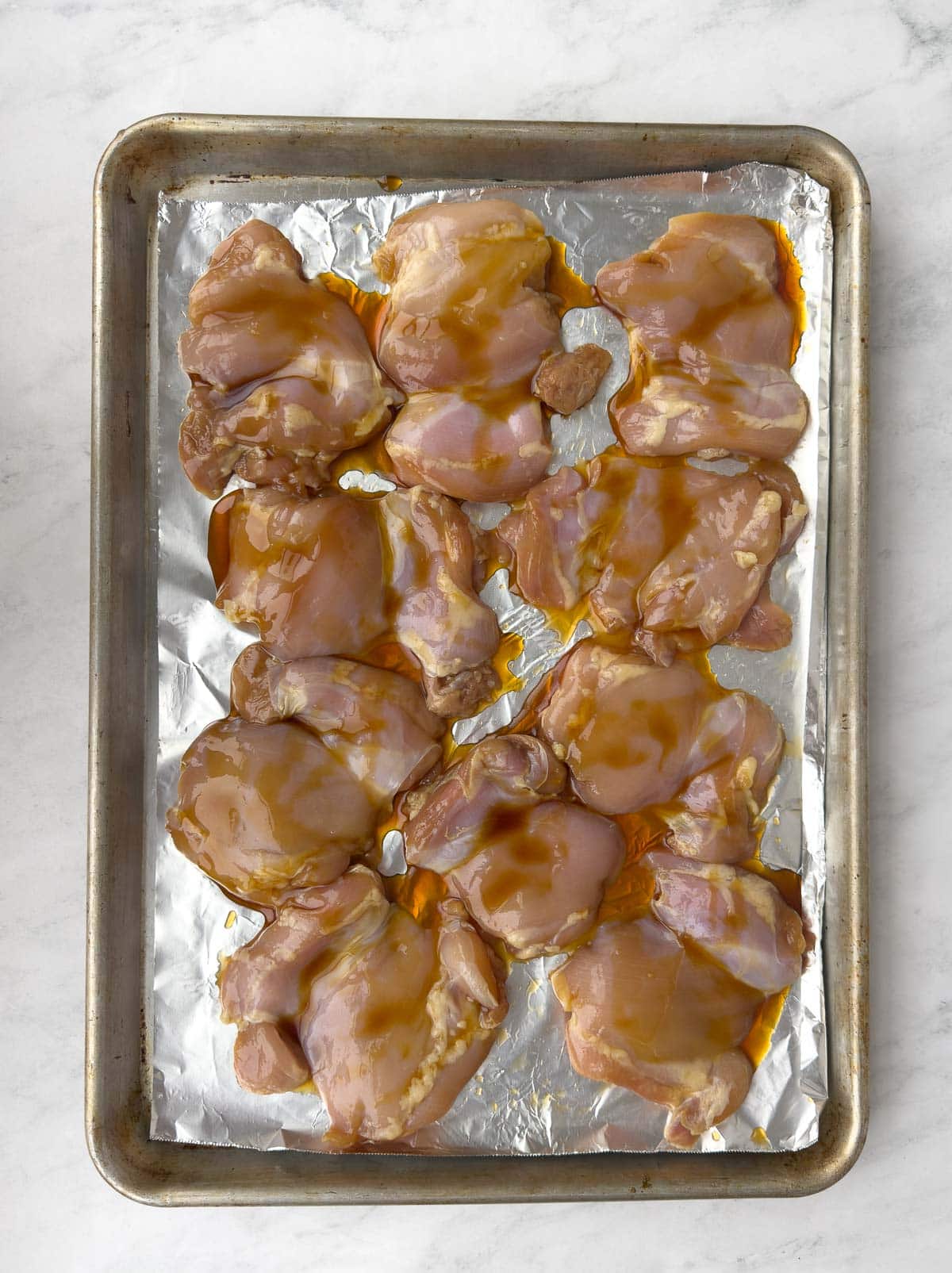 Baking marinated chicken thighs on a foil covered baking sheet. 
