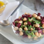 Colorful 3-bean salad in a glass bowl with a serving spoon.