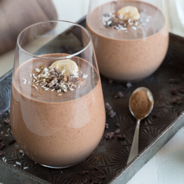 two chocolate smoothies in glasses on an antique tray.