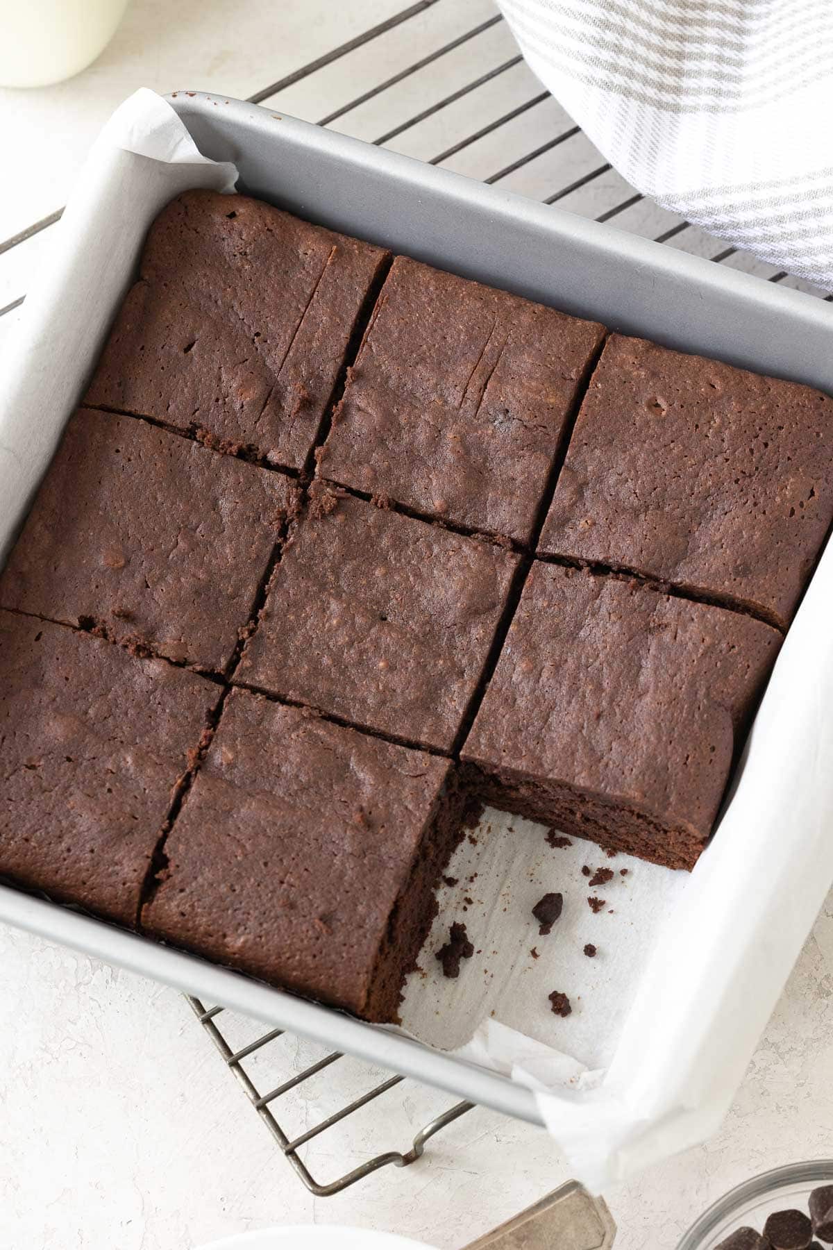 Sliced dark chocolate brownies in a square silver baking pan with one piece gone.