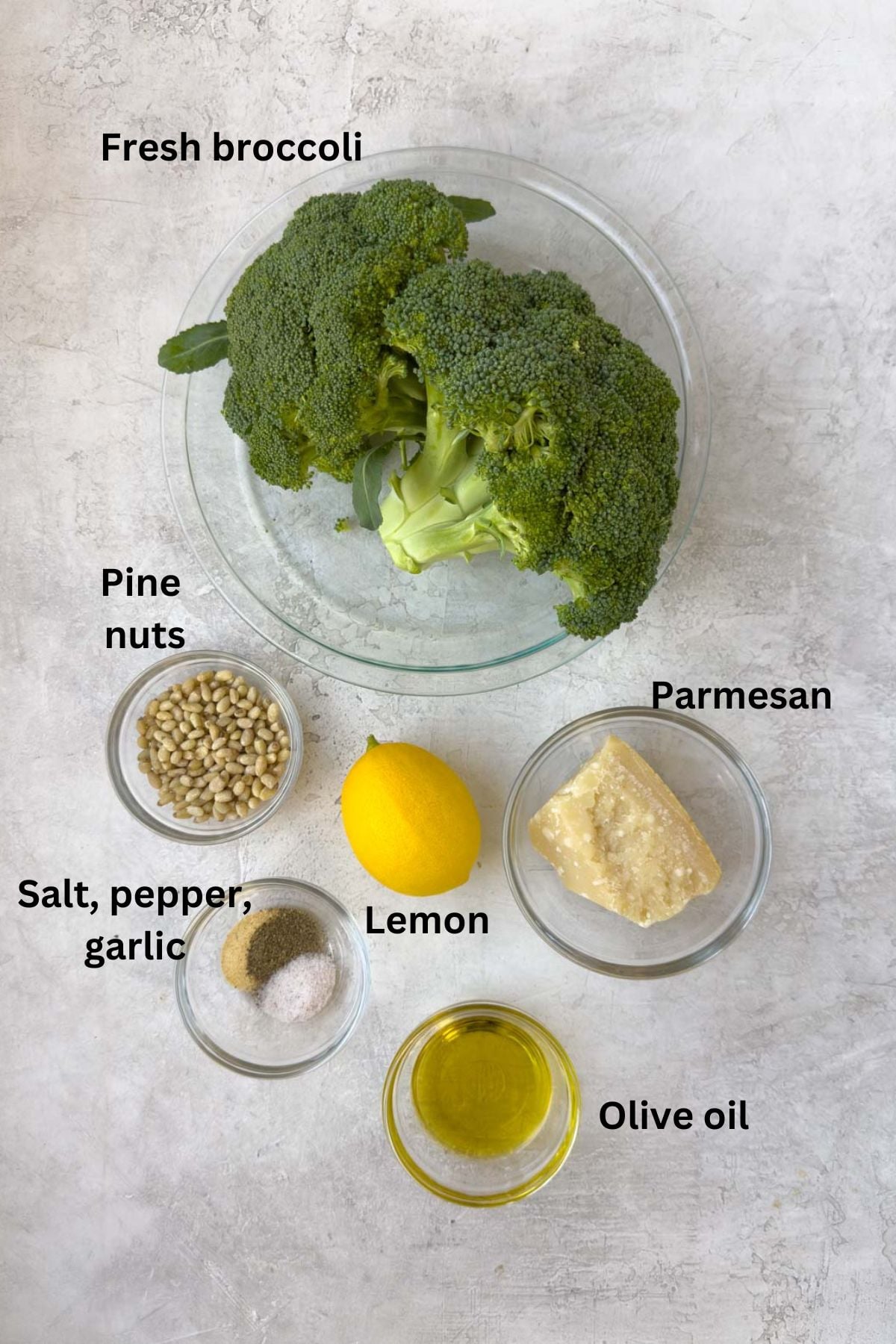 Ingredients for roasted broccoli on a counter in glass prep bowls.