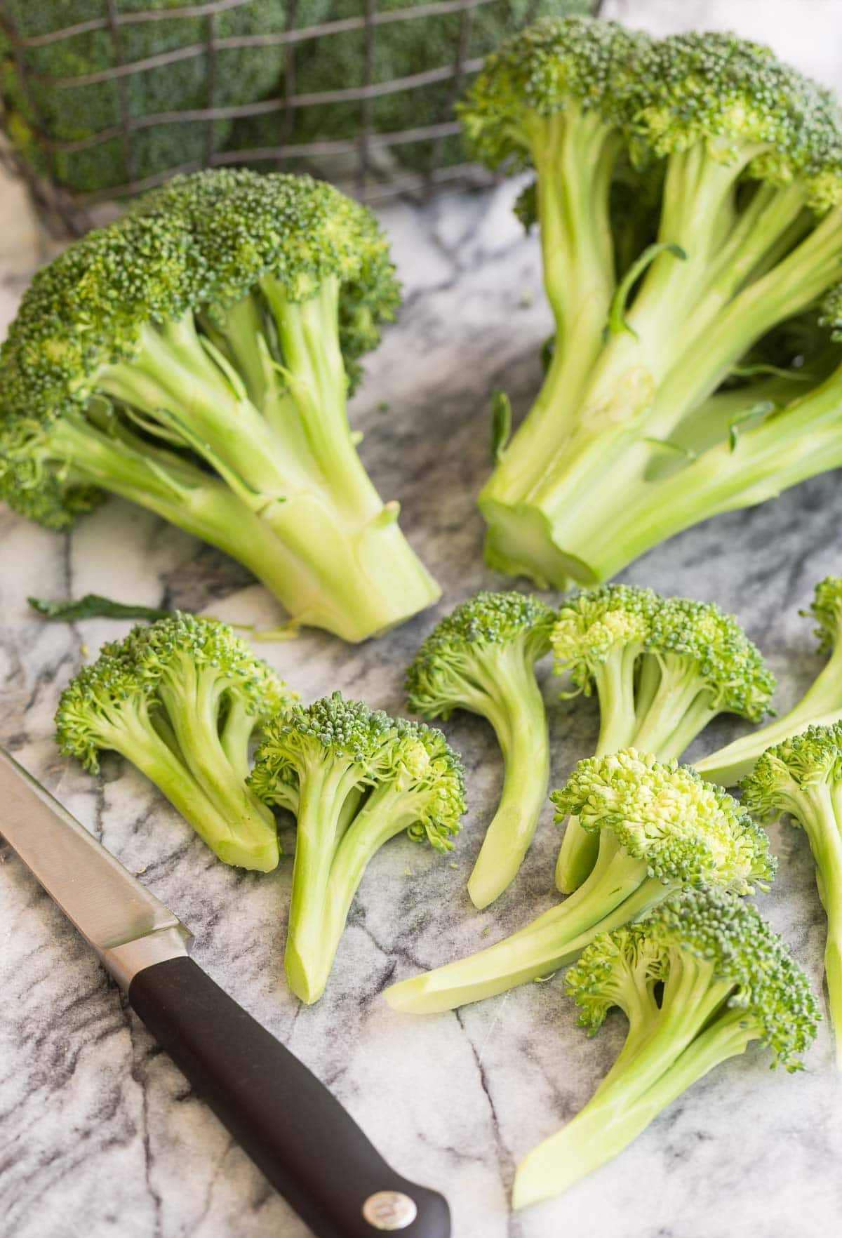 Trimming a head of green broccoli into smaller florets for roasting.