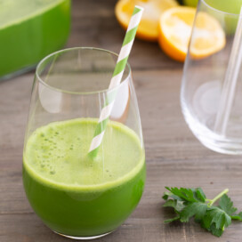 Detoxing green juice in a glass with a straw.