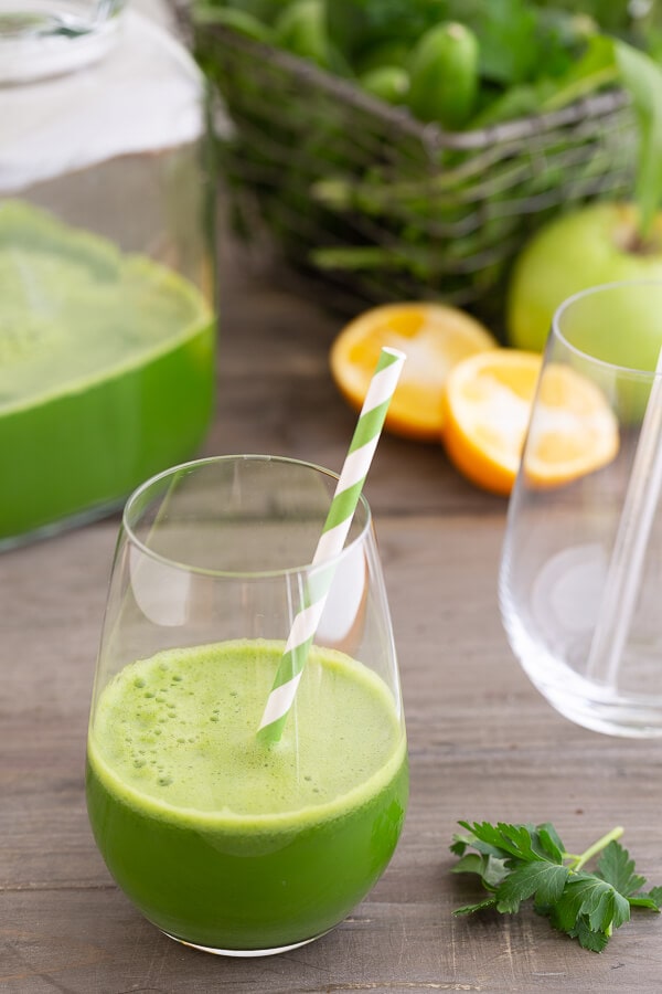 dandy detox green juice in a glass with straw.