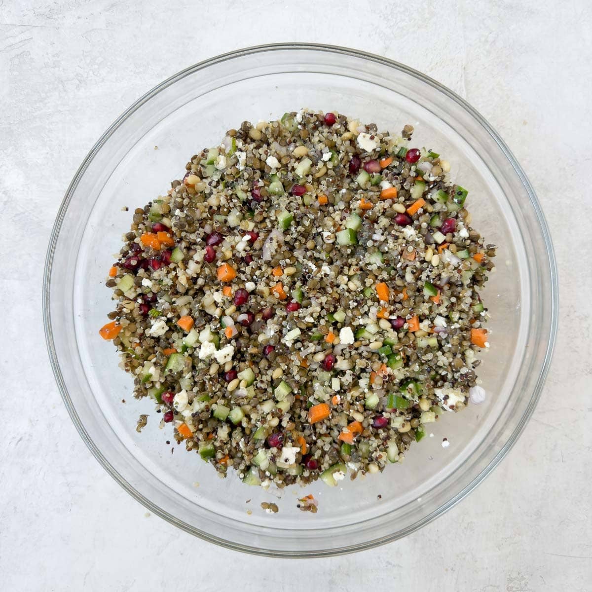 A lentil quinoa salad in a mixing bowl ready to be dressed for serving.