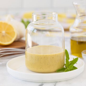 Golden creamy Greek salad dressing in a glass jar on a counter.