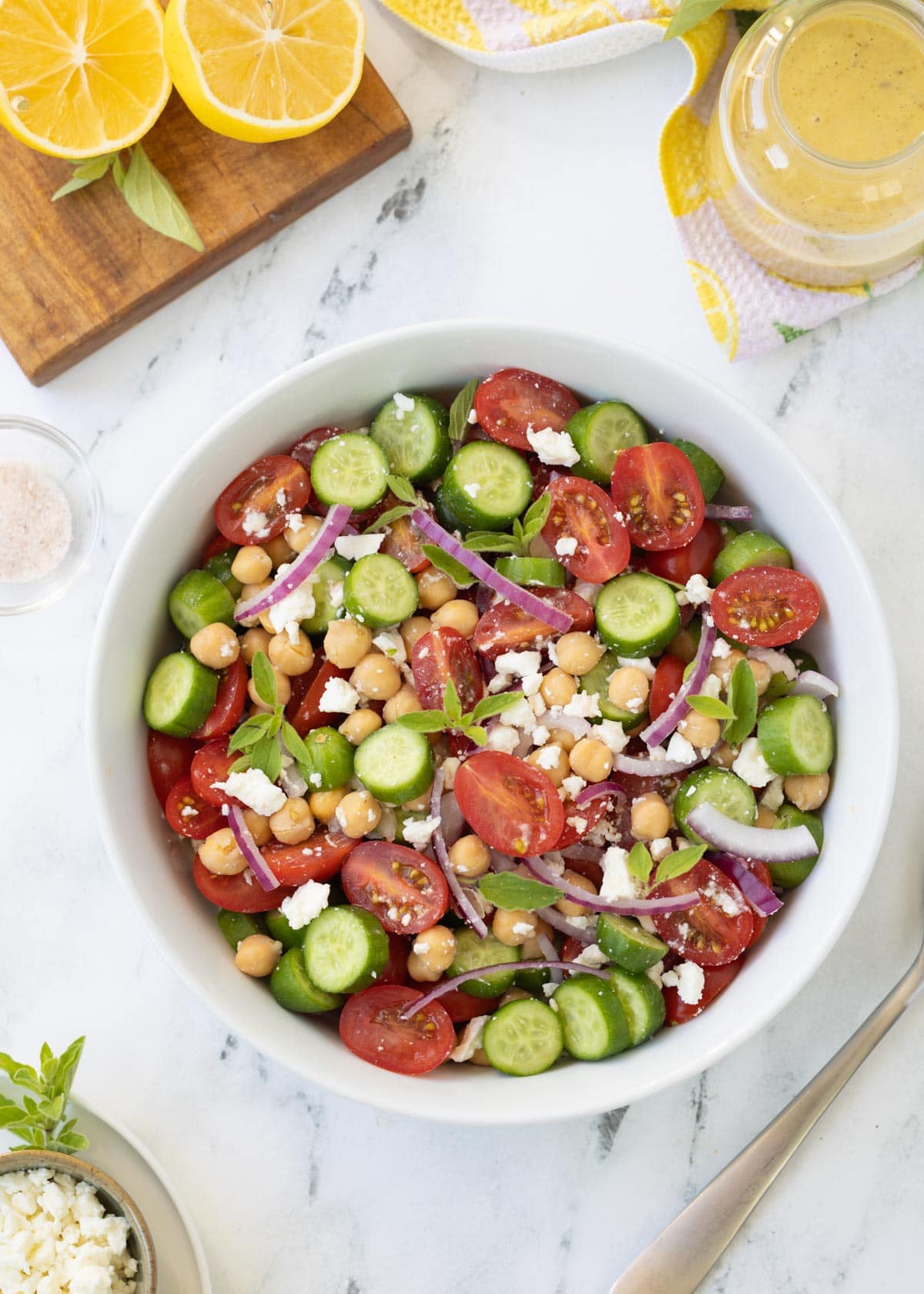 Greek cucumber and tomato salad with crumbled feta cheese, chickpeas, fresh oregano, and slivers of red onion
