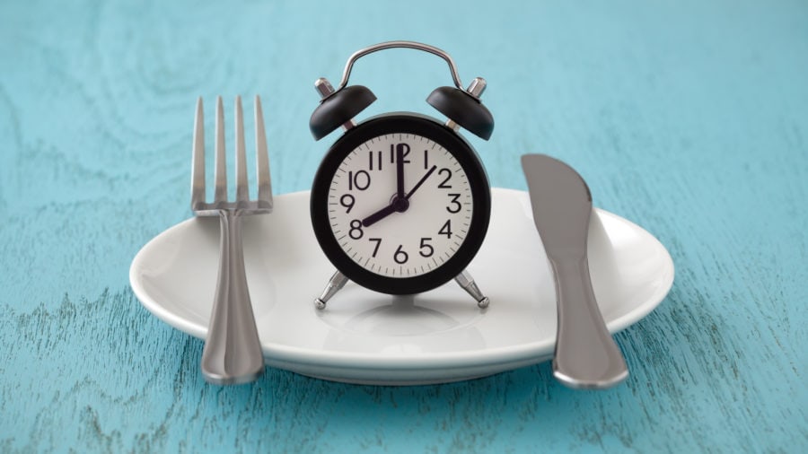 An alarm clock on a plate with silverware.