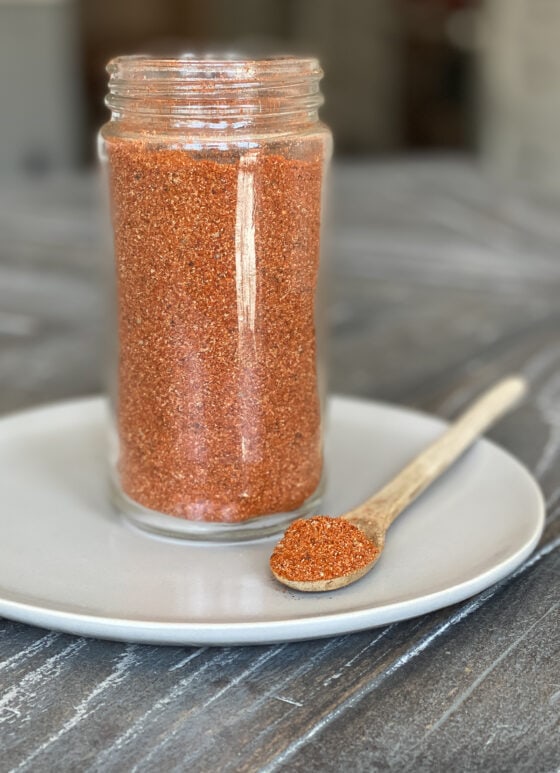 Dry rub mixed in a jar and on a spoon on a gray plate.