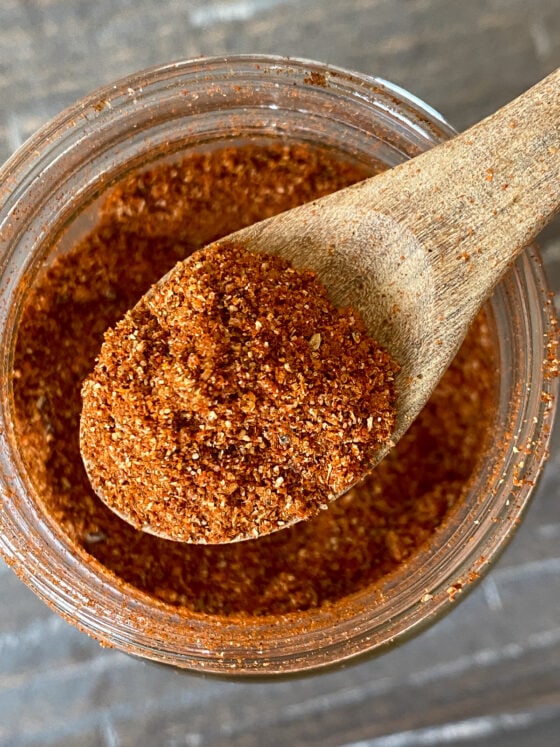 Spice dry rub on a spoon over a jar of the rub.