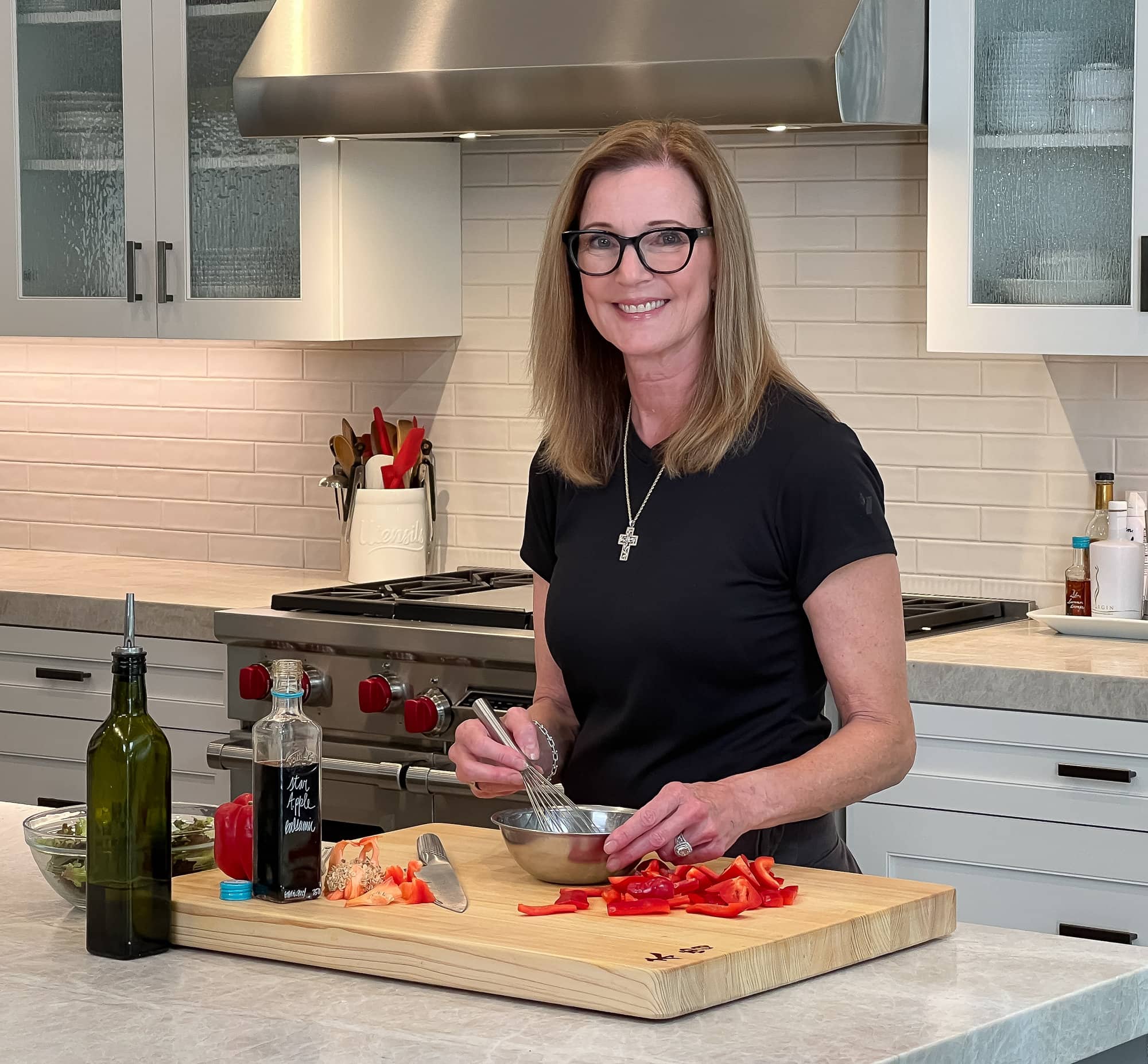 Chef Sally Cameron in her kitchen at a cutting board, making vinaigrette. 