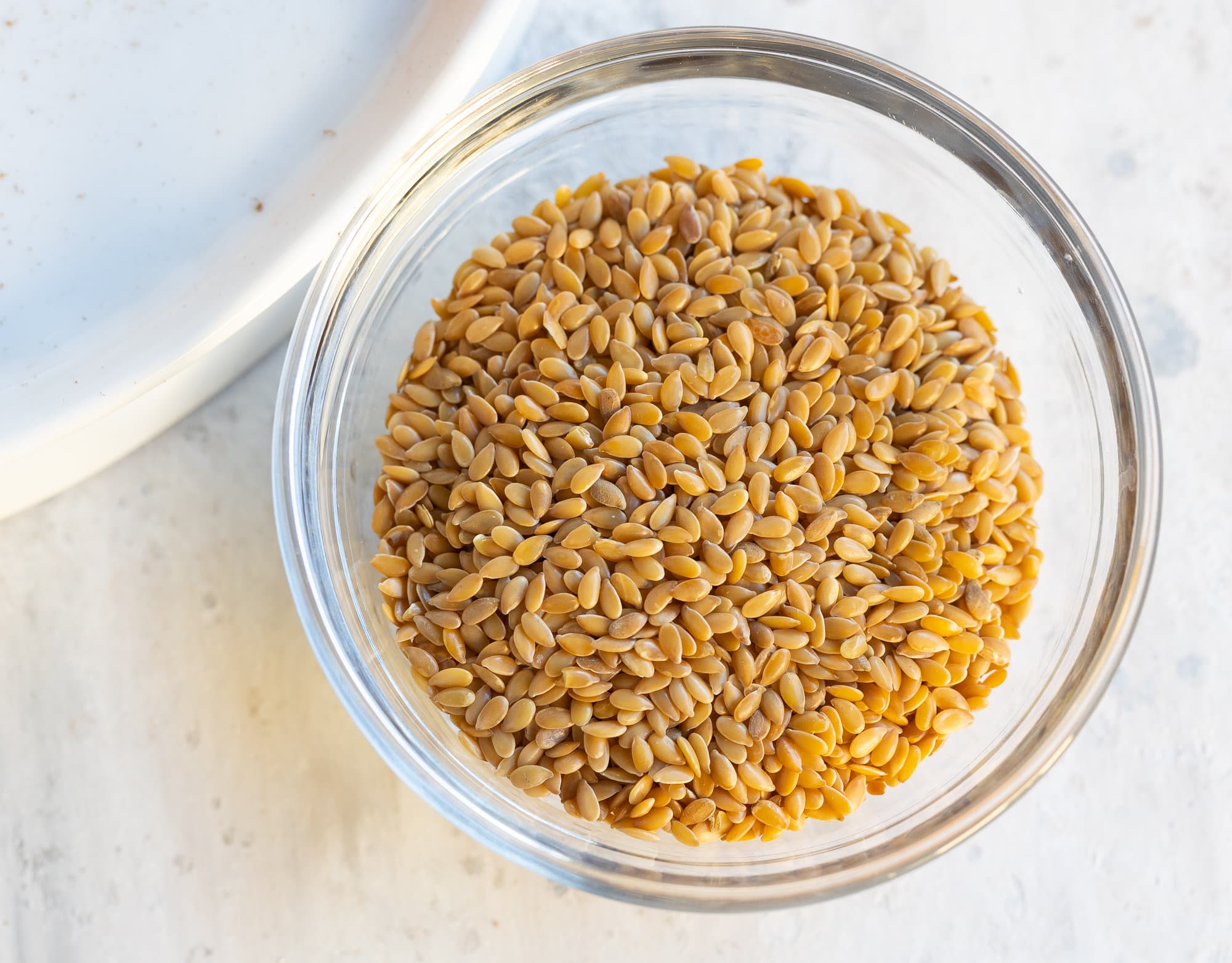 A small glass bowl of whole golden flaxseed before grinding. 