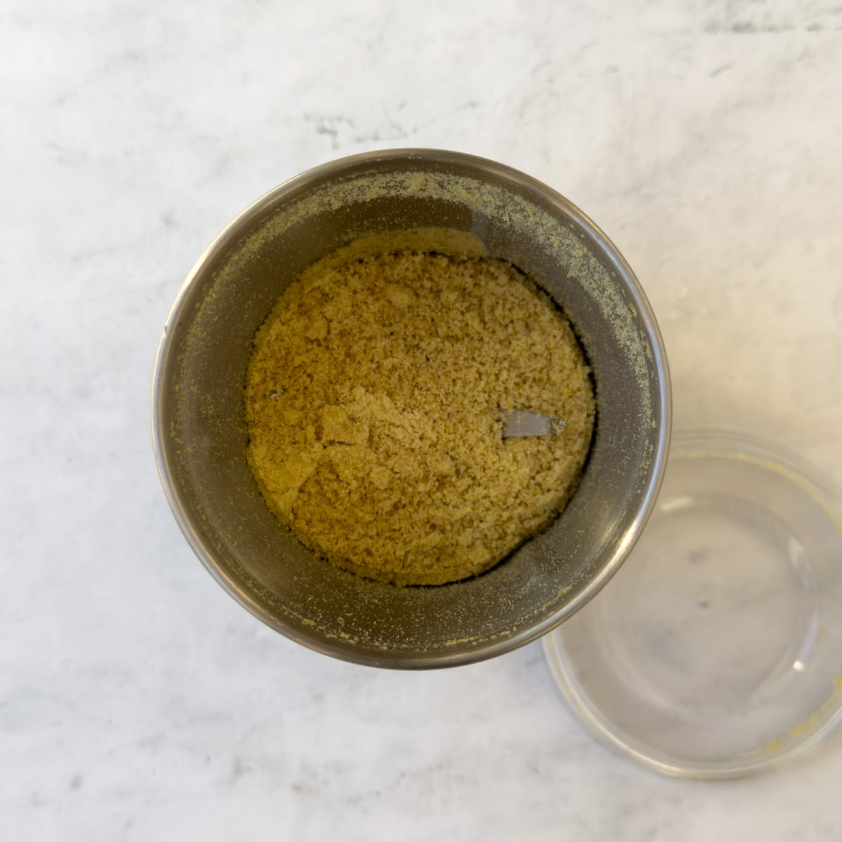 Golden ground flaxseed in a small hand-held grinder container.
