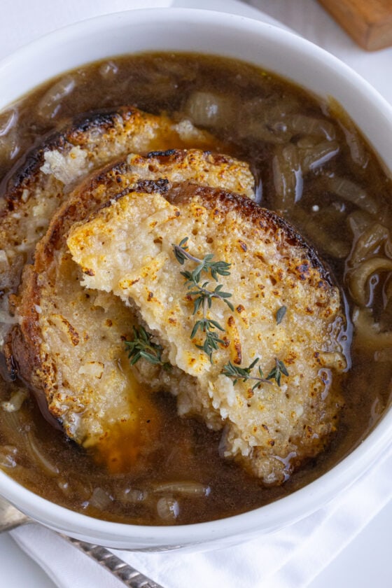 Close up of French onion soup, rich broth and crusty cheese croutons.