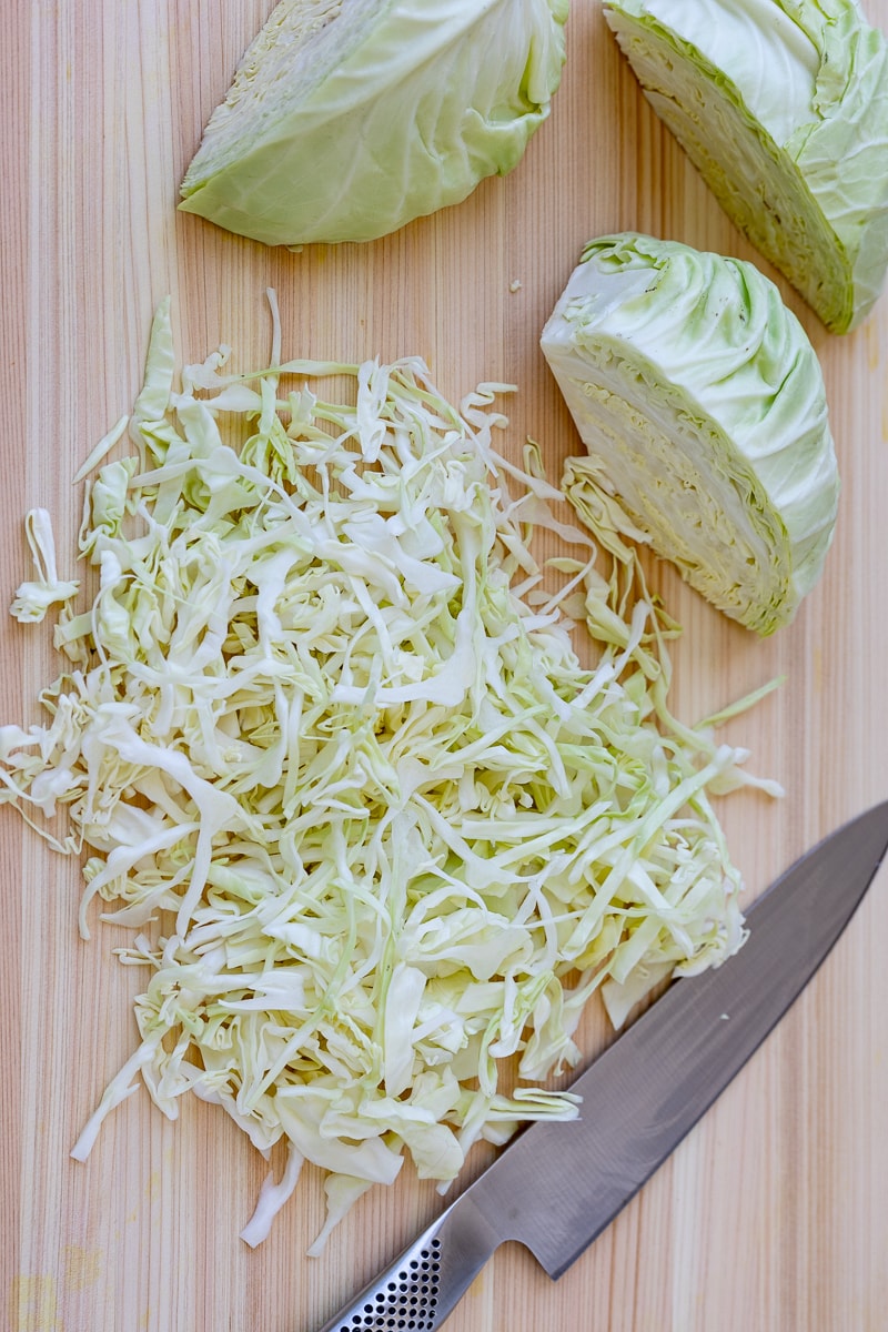 sliced cabbage for coleslaw on a cutting board.