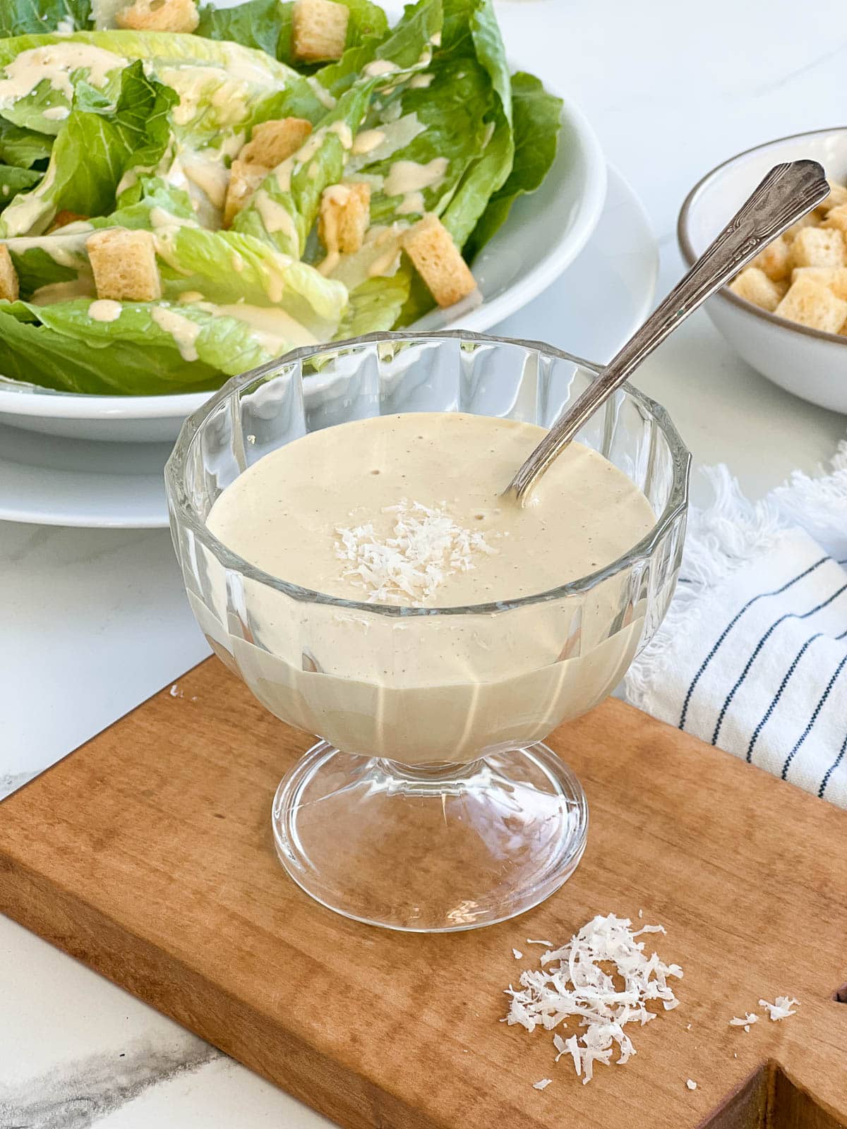 Caesar dressing in a glass bowl with spoon.