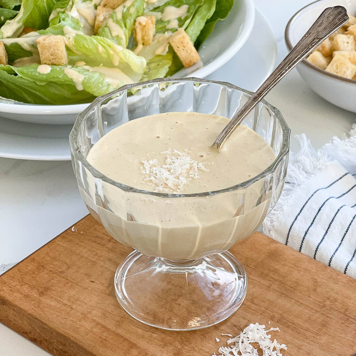 A bowl of caesar dressing with spoon.